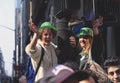 Happy young women with green bowler hats cheering and waving at St. PatrickÃ¢â¬â¢s Day parade in the streets.